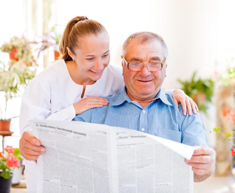 Proveer at Heritage Woods | Happy senior man reading newspaper with caregiver